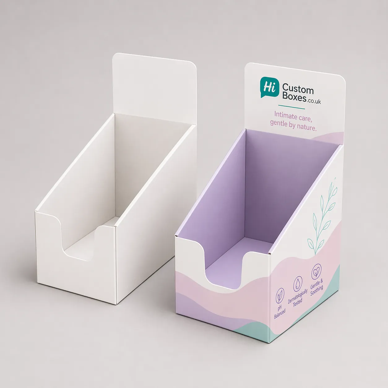 Two rectangular cardboard boxes, one plain and one with professional purple floral feminine care branding. class=